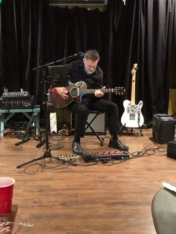 Craig Gleason performing on stage with acoustic guitar